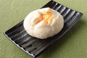 丸い白パンのてっぺんに十字の切れ目を入れ、外に広げたところにオレンジのチーズクリームが。