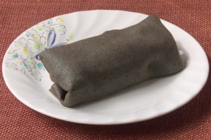 黒い生地で春巻状に巻き上げられたクレープ。