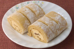 打ち粉を纏ったきなこ色の求肥で覆われたロールケーキ。