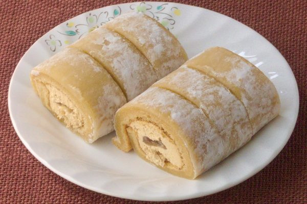 打ち粉を纏ったきなこ色の求肥で覆われたロールケーキ。