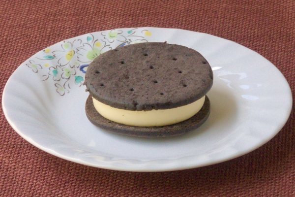 黒い円形クッキー2枚でサンドされた、薄黄色の分厚いクリーム。