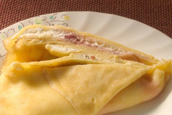 折りたたまれた生地の中には純白のホイップと赤いイチゴソース。